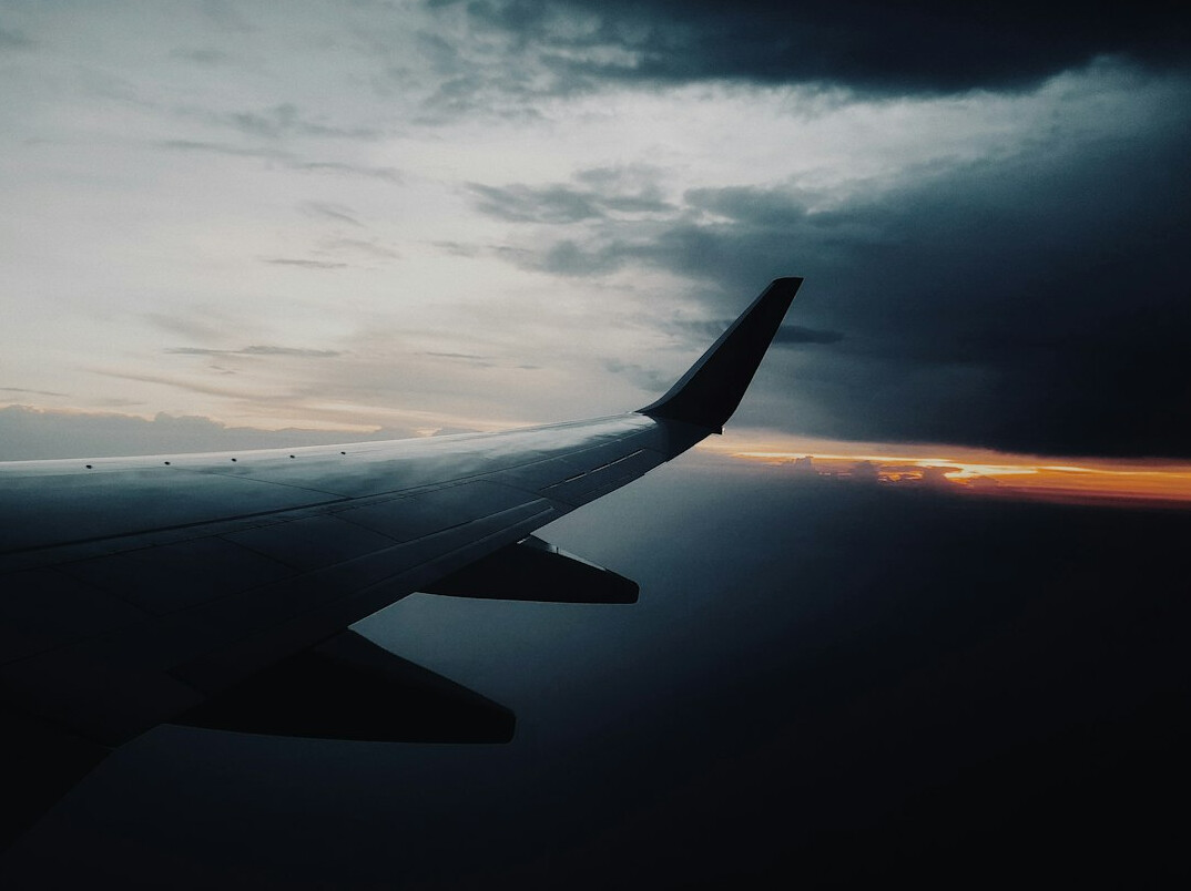 Airplane wing above clouds at sunrise